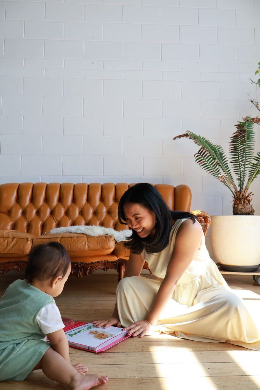 Mum in the Butter dress sitting on the floor, reading a picture book with her baby